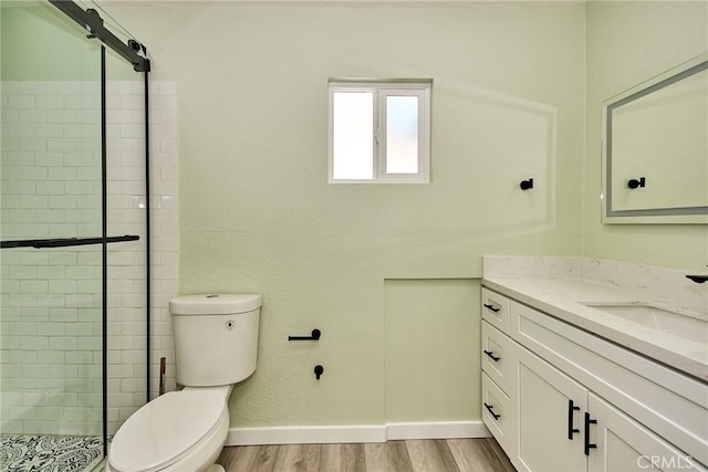 bathroom featuring baseboards, toilet, a shower stall, vanity, and wood finished floors