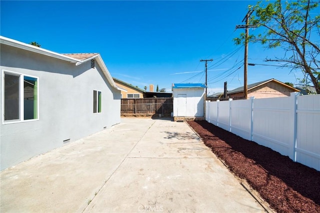 view of yard featuring an outbuilding, a shed, a fenced backyard, a patio, and driveway