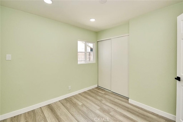unfurnished bedroom with light wood-style floors, a closet, and baseboards
