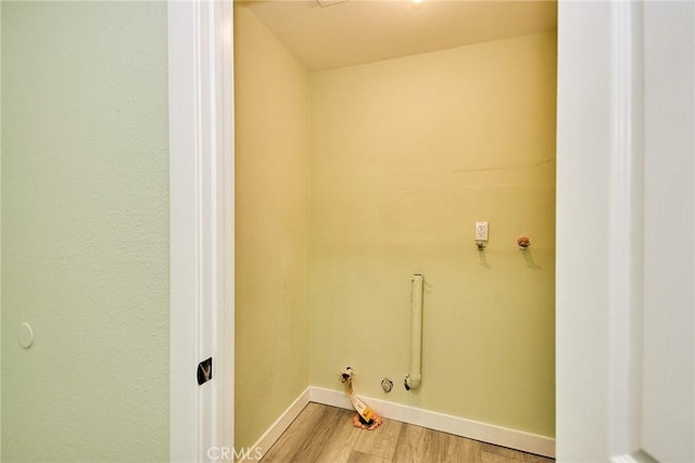 clothes washing area with laundry area, light wood finished floors, gas dryer hookup, and baseboards