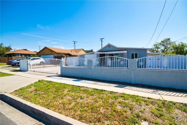 view of front of house with concrete driveway, a gate, and a fenced front yard