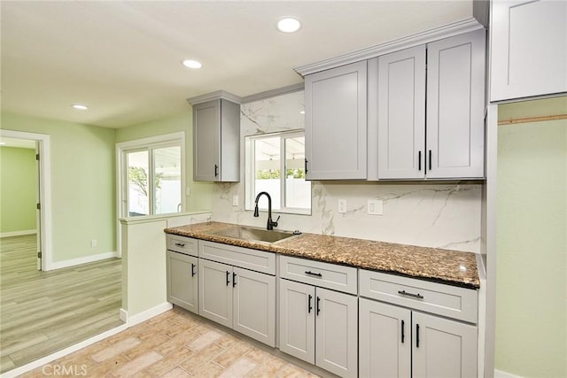 kitchen featuring baseboards, recessed lighting, light wood-style flooring, gray cabinetry, and a sink