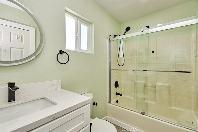 bathroom with bath / shower combo with glass door, vanity, and toilet