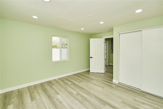 unfurnished bedroom featuring light wood-type flooring, a closet, baseboards, and recessed lighting