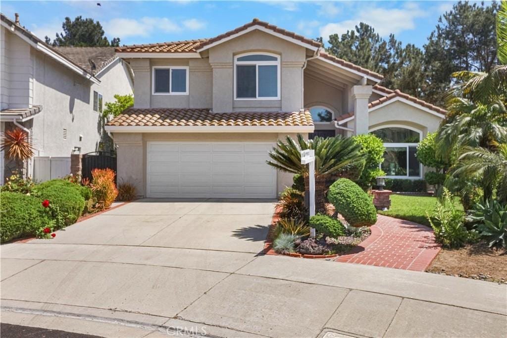mediterranean / spanish-style house with concrete driveway, stucco siding, an attached garage, a tiled roof, and fence