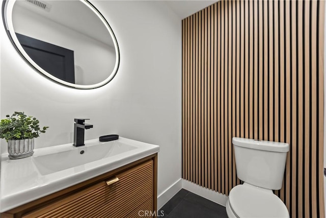 bathroom with toilet, visible vents, baseboards, wallpapered walls, and vanity