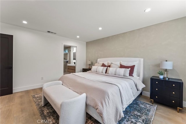 bedroom with light wood-style flooring, baseboards, visible vents, recessed lighting, and ensuite bath