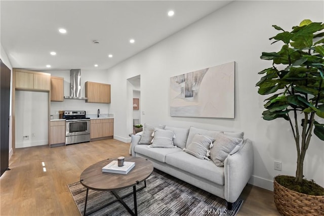 living area with baseboards, light wood-style floors, and recessed lighting