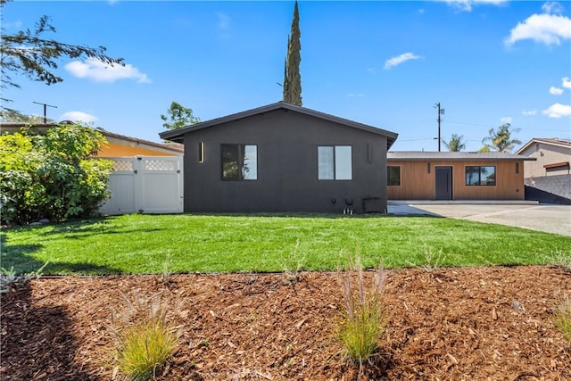 rear view of house with a gate, a lawn, fence, a patio, and stucco siding