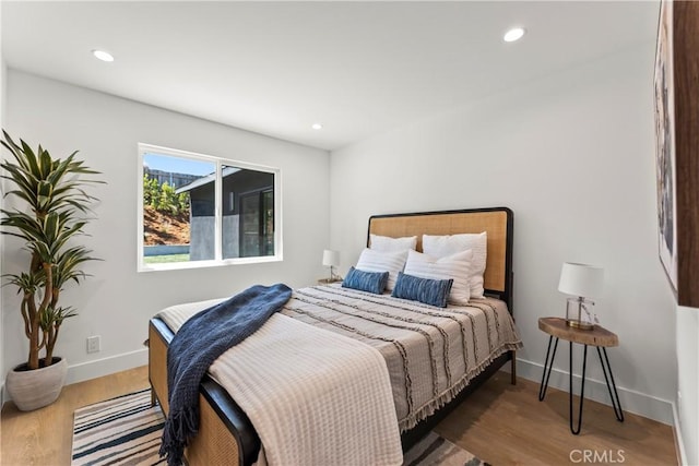 bedroom featuring baseboards, wood finished floors, and recessed lighting