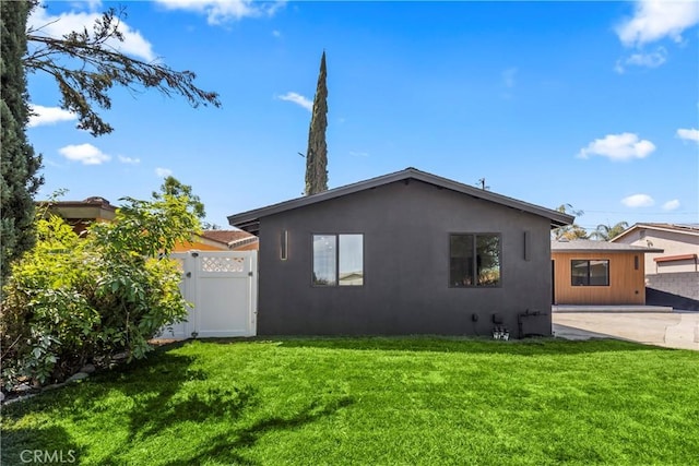 view of home's exterior featuring stucco siding, a gate, fence, and a lawn