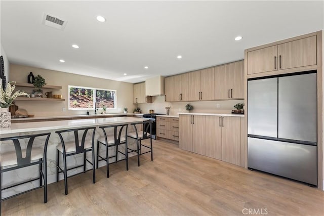 kitchen with appliances with stainless steel finishes, light brown cabinetry, and light countertops