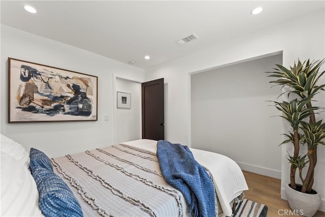 bedroom featuring baseboards, wood finished floors, visible vents, and recessed lighting