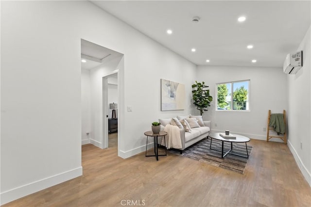 living area with an AC wall unit, baseboards, light wood finished floors, and recessed lighting