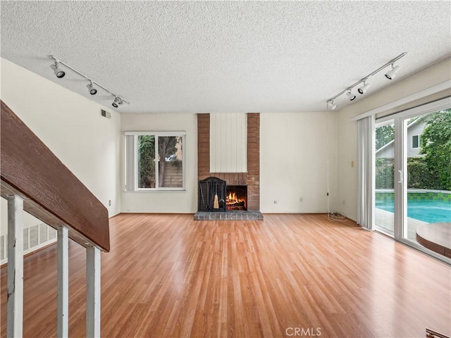 25582 Old Course Way, Valencia, CA 91355 - unfurnished living room with rail lighting, light wood-style floors, a textured ceiling, and a fireplace