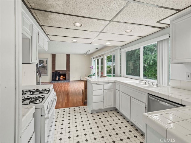 25582 Old Course Way, Valencia, CA 91355 - kitchen with white range with gas stovetop, open floor plan, tile counters, white cabinetry, and dishwasher