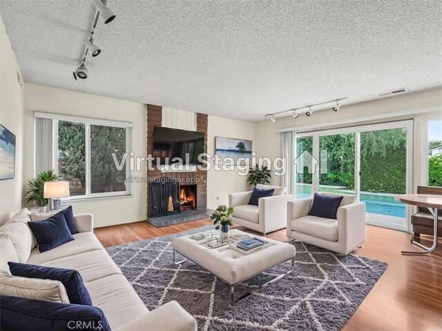 25582 Old Course Way, Valencia, CA 91355 - living area with track lighting, plenty of natural light, wood finished floors, a fireplace, and a textured ceiling