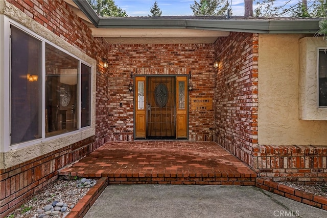 entrance to property featuring stucco siding and brick siding