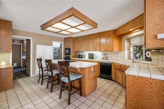 kitchen with tile counters, tasteful backsplash, black appliances, and light tile patterned flooring