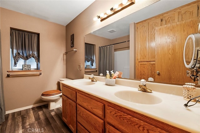 bathroom with baseboards, a sink, toilet, and wood finished floors