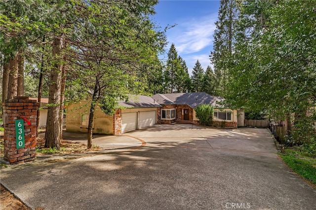 ranch-style home with a garage, fence, and driveway