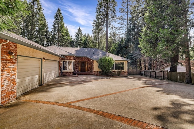view of front of house featuring a garage, brick siding, driveway, and fence