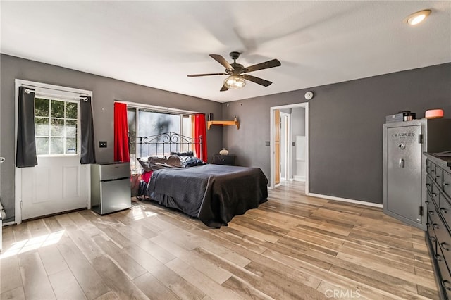 bedroom featuring light wood-type flooring, a ceiling fan, and freestanding refrigerator