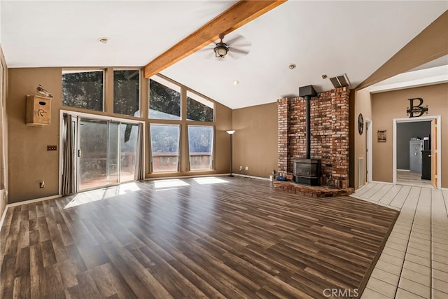 unfurnished living room featuring beam ceiling, a wood stove, ceiling fan, and wood finished floors
