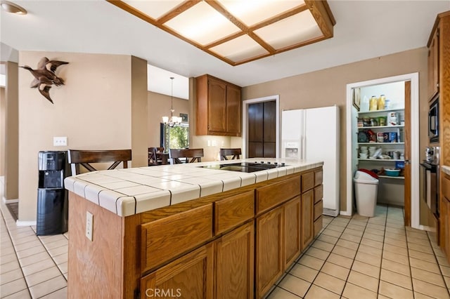kitchen featuring an inviting chandelier, light tile patterned flooring, brown cabinets, tile countertops, and black appliances
