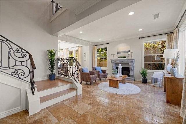 living area featuring baseboards, ornamental molding, stone tile flooring, and stairs