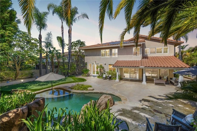 pool at dusk featuring a patio and an outdoor pool