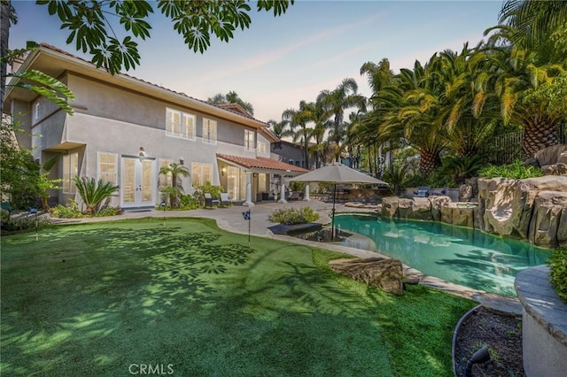 pool at dusk featuring a patio, an outdoor pool, and french doors