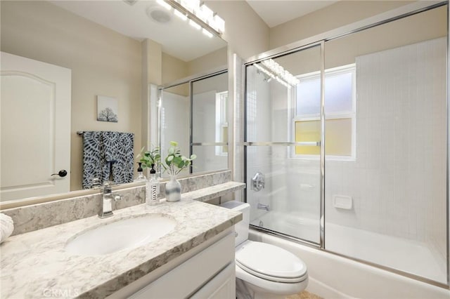 bathroom featuring toilet, vanity, and shower / bath combination with glass door