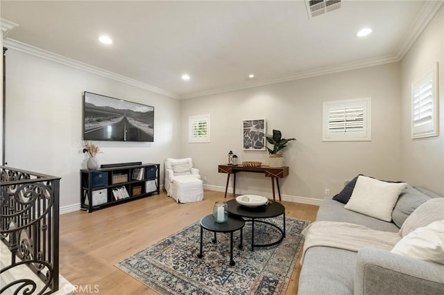 living room with crown molding, visible vents, light wood-style flooring, and baseboards