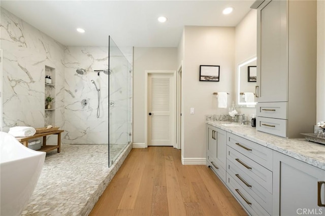 full bath with a freestanding bath, recessed lighting, vanity, wood finished floors, and a marble finish shower