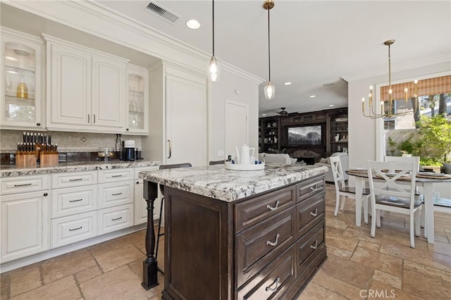 kitchen featuring visible vents, ornamental molding, stone tile flooring, and dark brown cabinetry