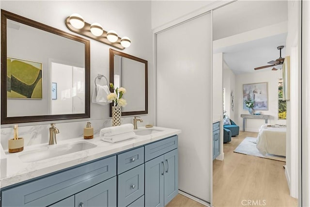 full bathroom featuring double vanity, a sink, connected bathroom, and wood finished floors