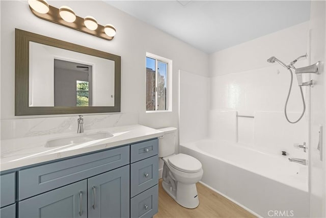 full bath featuring toilet, shower / bath combination, wood finished floors, and vanity
