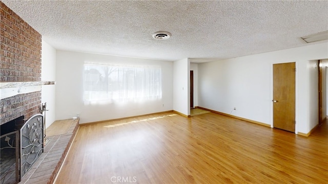 unfurnished living room with visible vents, baseboards, wood finished floors, and a brick fireplace