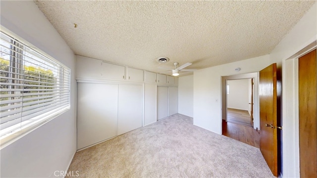 unfurnished bedroom with a textured ceiling, a closet, visible vents, and carpet floors