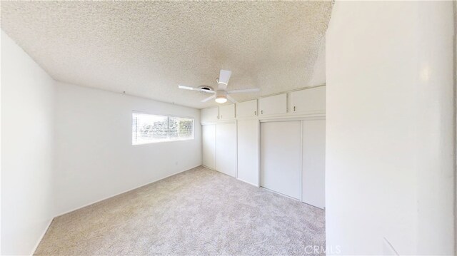 unfurnished bedroom with carpet floors, ceiling fan, a closet, and a textured ceiling