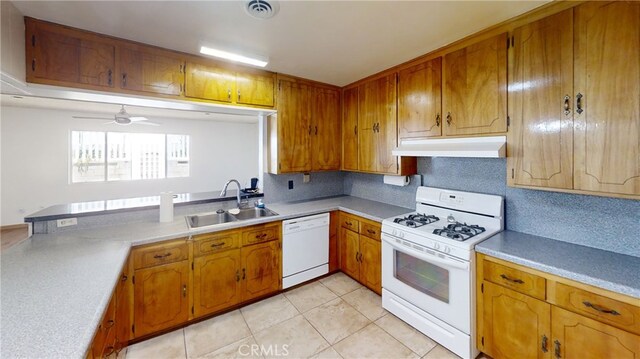 kitchen featuring brown cabinets, under cabinet range hood, a sink, and white appliances