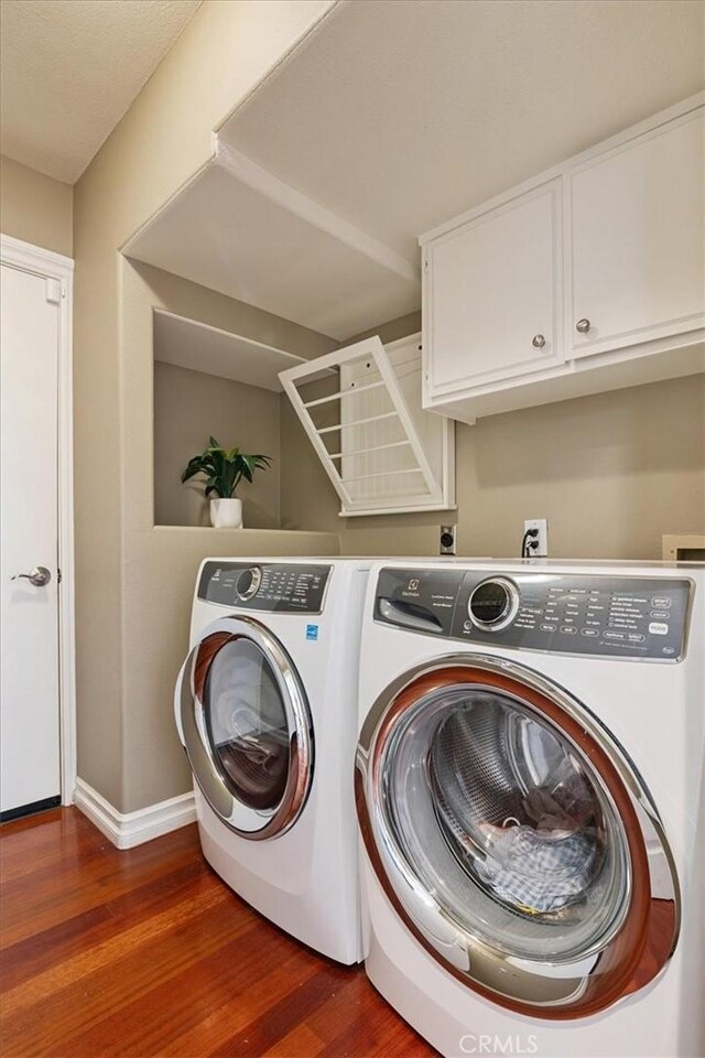 4 Bastia, Laguna Niguel, CA 92677 - clothes washing area featuring washer and dryer, baseboards, wood finished floors, and cabinet space