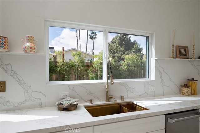 kitchen featuring a sink, tasteful backsplash, white cabinetry, light stone counters, and dishwasher