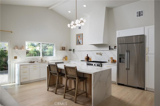 kitchen with light wood finished floors, white cabinets, visible vents, stainless steel refrigerator with ice dispenser, and high vaulted ceiling