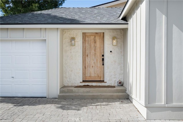 view of exterior entry featuring roof with shingles