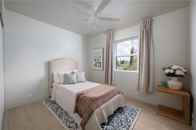bedroom featuring light wood-style flooring, baseboards, and ceiling fan