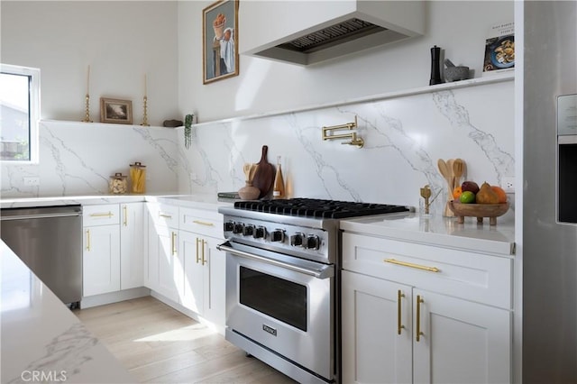 kitchen featuring white cabinets, stainless steel appliances, light wood-type flooring, decorative backsplash, and custom range hood