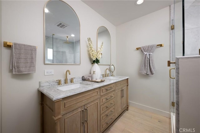 full bathroom featuring wood finished floors, visible vents, an enclosed shower, and a sink
