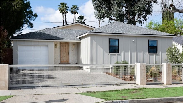 view of front of property featuring roof with shingles, a fenced front yard, concrete driveway, a garage, and board and batten siding